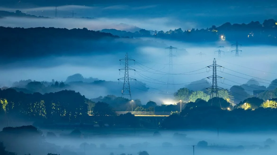 Pylons in a moody mountain scene at dusk